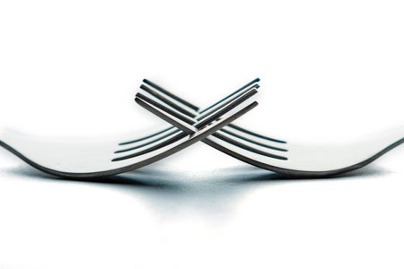 Engraved silverware fork set of two placed face to face crossing their teeth isolated on white backgroundの写真素材