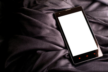 Smartphone with blank white display for mockups on a folded satin black cloth studio photographyの写真素材