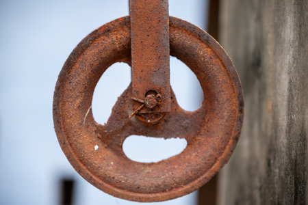A detailed view of an aged, rusty pulley showcasing textures and wear, contrasting against a blurred background, evoking themes of industrial history, decay, and the passage of time.の写真素材