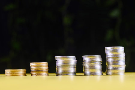 Stacked coins of varying heights symbolizing financial growth, investments, and wealth accumulation. Representations of economic success, savings management, or monetary concepts under a symbolic light.の写真素材