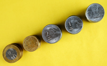 Stacks of coins in neat rows on a bright yellow background represent financial growth and savings. This composition is ideal for illustrating concepts like investment, economy, and monetary planning.の写真素材
