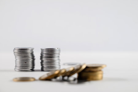Stacks of silver and golden coins arranged on a white surface, representing concepts of wealth, savings, and financial growth. Perfect for illustrating fiscal success, investments, and monetary themes.の写真素材