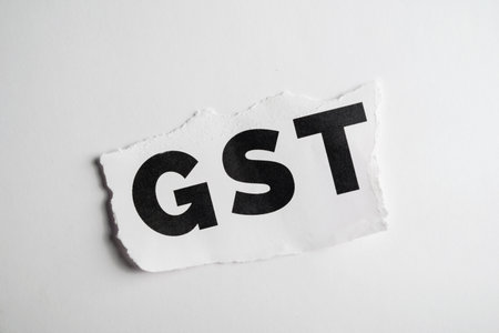 A textual representation of the word 'GST' printed and displayed on torn paper, isolated against a clean white backdrop creating a minimalist and impactful visual emphasizing the concept.の写真素材