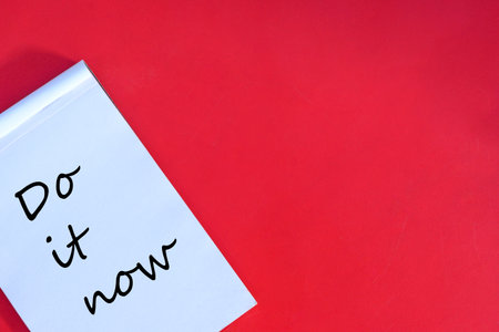Handwritten note reading 'Do it now' on a vivid red background, inspiring motivation and action. Simple and impactful composition highlighting personal responsibility and the importance of seizing the moment.の写真素材