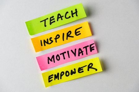 Four colorful sticky notes display motivational words like Teach, Inspire, Motivate and Empower, forming a compelling visual symbol of encouragement, growth mindsets, and personal development.の写真素材