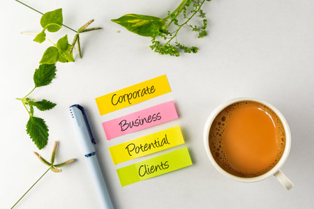 Organized workplace scene featuring sticky notes with key business terms, a cup of tea, and vibrant greenery, evoking productivity and fresh ideas.の写真素材