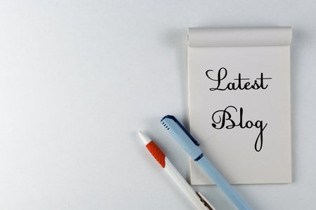 A notepad labeled 'Latest Blog' alongside two pens, portraying blogging and content creation...