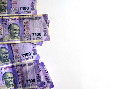 Multiple Indian 100 rupee banknotes displayed against a clean white background, symbolizing economy,...