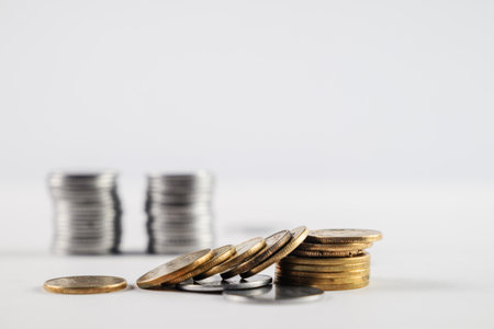 Stacks of silver and golden coins arranged on a white surface, representing concepts of wealth, savings, and financial growth. Perfect for illustrating fiscal success, investments, and monetary themes.の写真素材