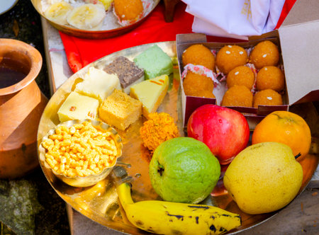 A vibrant arrangement of traditional Indian fruits and sweets displayed on a brass plate, symbolizing generosity and festivity, often accompanying rituals and celebrations as offerings to the divine.の写真素材