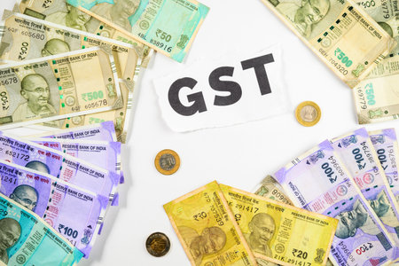 Top view of a collection of Indian currency notes and coins displayed beside a GST sign, symbolizing financial concepts related to GST and economic transactions in India.の写真素材