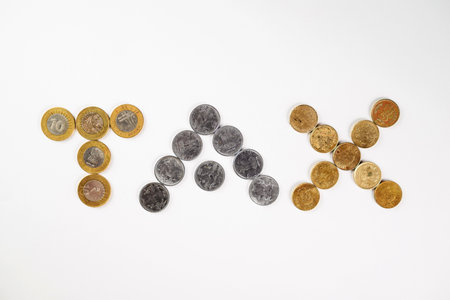 Close-up of coins creatively arranged to form the word 'tax' on a simple white surface. A concept for finance, taxes, and monetary discussions, represented through currency illustrations.の写真素材