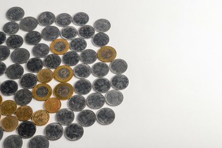 A collection of scattered silver and gold coins on a white surface, conveying concepts of money and finance.の写真素材