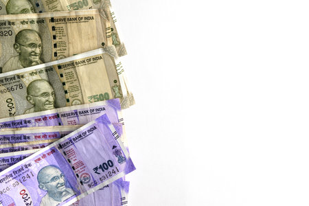 Close-up of multiple Indian rupee banknotes neatly arranged against a pure white background,...
