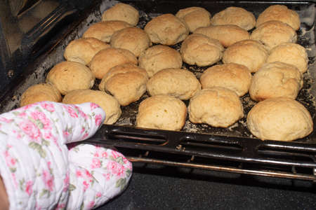 oven mitt pulling a black pan full of loaves from the ovenの写真素材