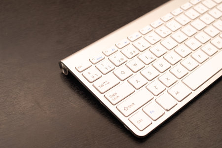 partial view of a gray and white PC keyboard, on a dark wood backgroundの写真素材