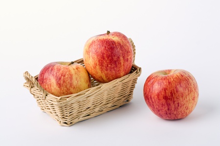apple in wicker basket isolated on whiteの写真素材