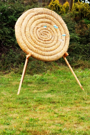 straw circle archery target with wooden arrows in it as competition conceptの写真素材