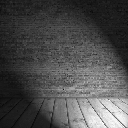 brick wall and wooden planks floor as black and white background interior background with black shadow and beam of spot light in the cornerの写真素材