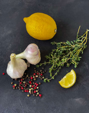 garlic, thyme, lemon and spices on a black concrete table