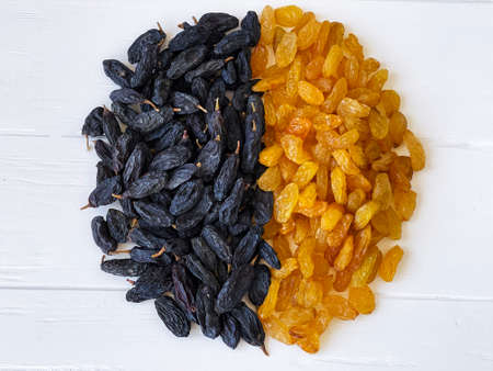 light and dark dried raisins on a white wooden tableの写真素材