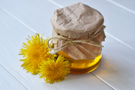 honey and yellow flowers on a white wooden tableの写真素材