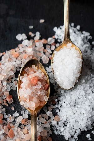 pink and sea white salt in spoons on black backgroundの写真素材