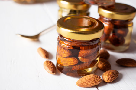 almonds in a jar in honey on a wooden tableの写真素材