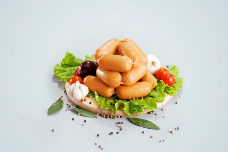 A composition of different sorts of sausages on the wood board with fresh vegetableの写真素材