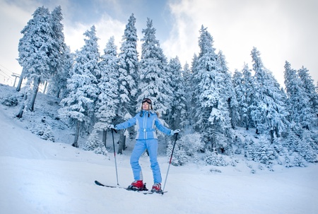 skiing on snow-covered slopes among the firs in the forestの写真素材