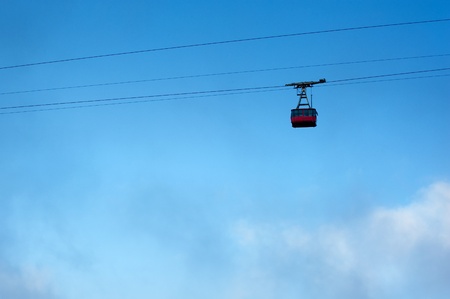 ski lift is moving up high in the sky above the cloudsの写真素材
