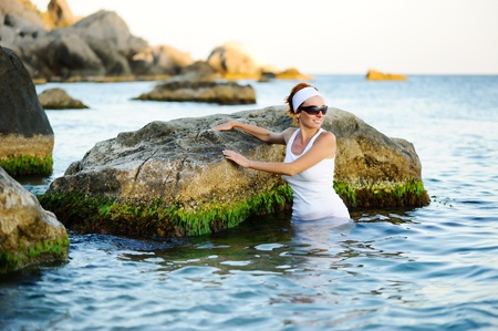 Beautiful woman splashing in the sea near stonesの写真素材