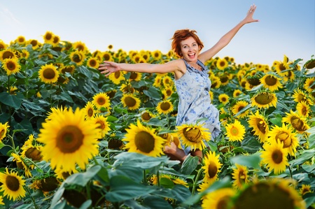 young beautiful woman on blooming sunflower field in summerの写真素材