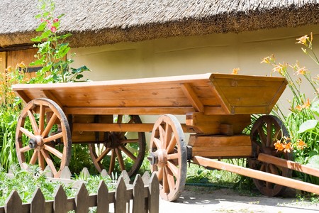 Cart is wooden near the shed of covered a straw
