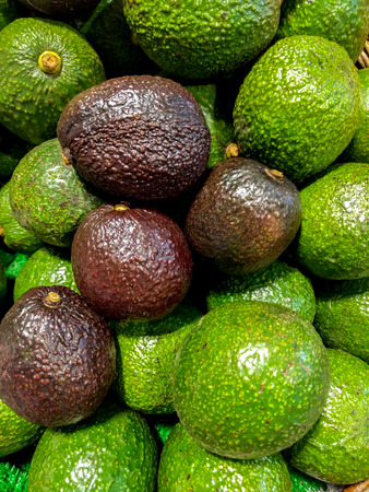 Close up Green and Red Avocados From Top View in The Basket at Market.