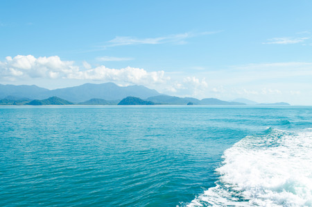 Horizontal of Seascape including Forest Mountain, Blue Sky and Wave of Water Foam in Ocean.の写真素材