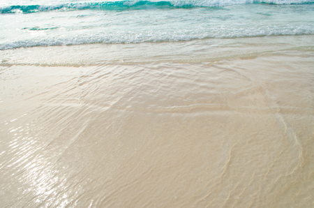 Close up Wave of The Ocean, White Sand on Summer Beach and Surface Water Foam.の写真素材