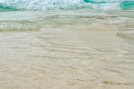 Close up Wave of The Ocean, White Sand on Summer Beach and Surface Water Foam.の写真素材