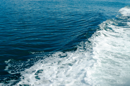 A Blue Trail Waves Surface Foam of Cruise Line After Speed Boat Passing in Ocean with Beautiful Blue Sky Background.の写真素材