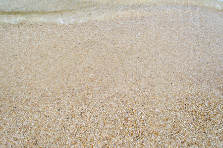 Close up Wave of The Ocean, White Sand on Summer Beach and Surface Water Foam.の写真素材