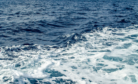 A Blue Trail Waves Surface Foam of Cruise Line After Speed Boat Passing in Ocean with Beautiful Blue Sky Background.の写真素材