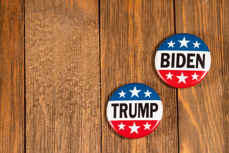 Washington DC--July 5, 2020; red white and blue round Trump and Biden 2020 American presidential campaign buttons sit beside each other on wooden table topのeditorial素材