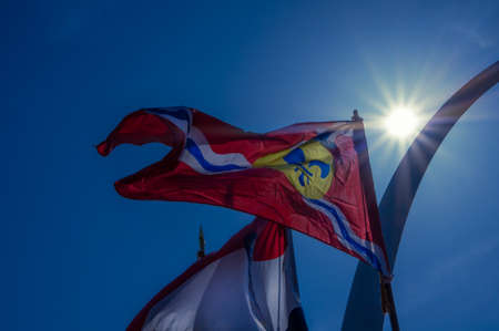 Saint Louis city and Missouri state flags flying in front of the Gateway Arch with sun and blue sky in the backgroundsの写真素材