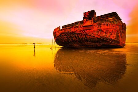 A boy dwarfed by a huge barge   shipの写真素材