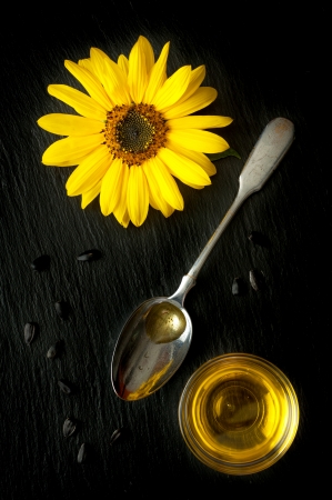 Sunflower oil, sunflower and sunflower seeds on a black backgroundの写真素材