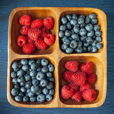 Raspberries and blueberries in a wooden bowlの写真素材