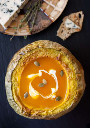 Pumpkin soup baked in a pumpkin on a black slate chalkboardの写真素材