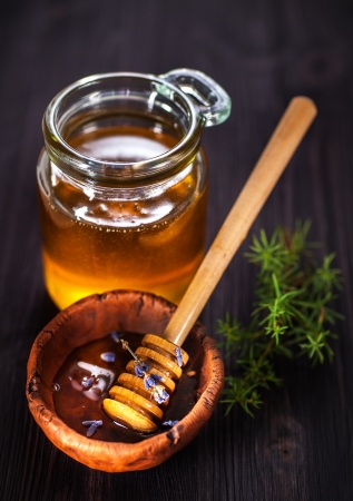 Pot of honey with lavender and a spoon for honey on a wooden backgroundの写真素材