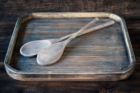 Old wooden spoon in a vintage wooden trayの写真素材