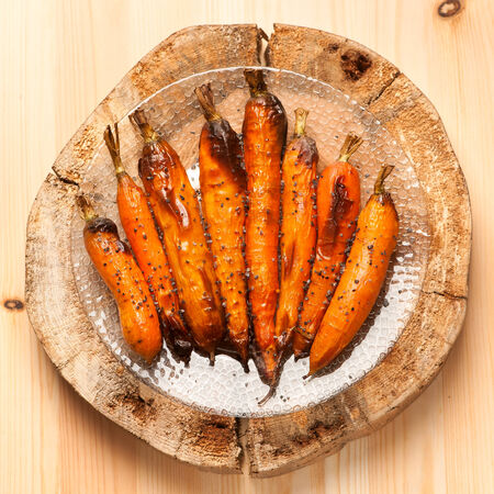 Baked carrots on wooden board in rustic styleの写真素材
